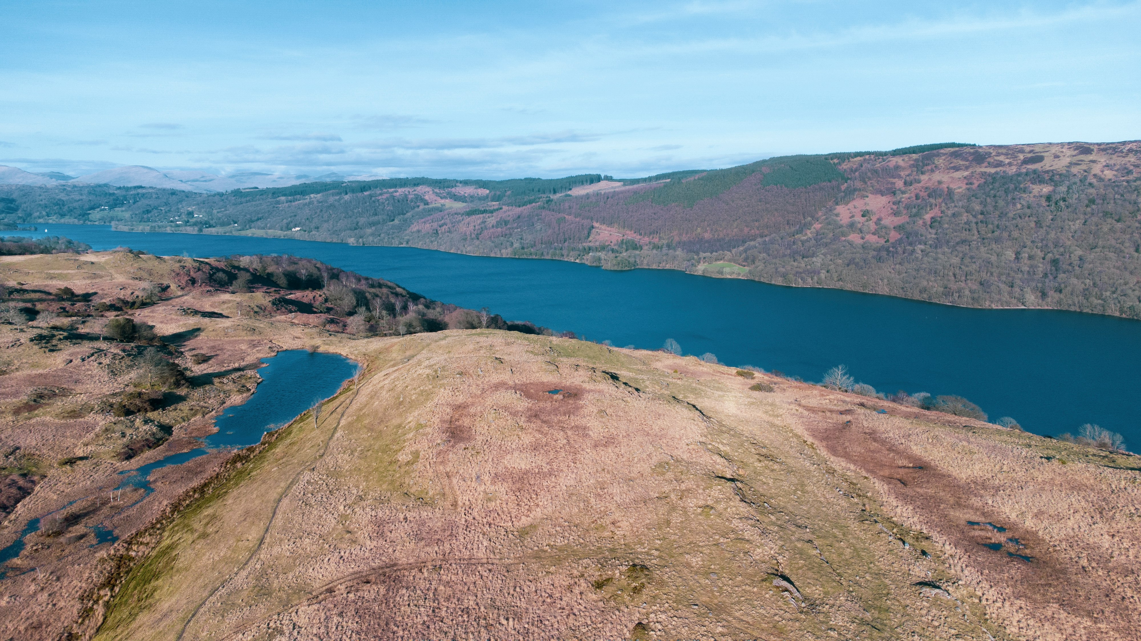 brown mountain near body of water during daytime